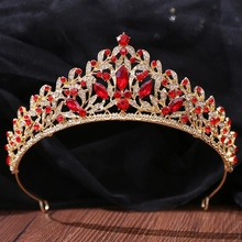 Close-up of golden Baroque bridal crown with red and clear crystals on a wooden base