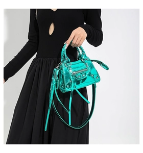 Detail of green metallic leather handbag with silver studs and braided handles