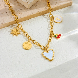Vintage gold chain charm bracelet with heart, cherry, and sun charms on a stone slab