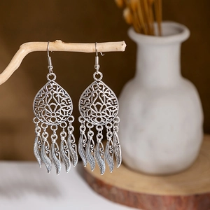 Silver hollow teardrop earrings with metal tassels hanging on a decorative branch