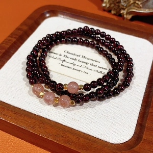 Detail of garnet beaded bracelet with strawberry quartz and golden metal spacers