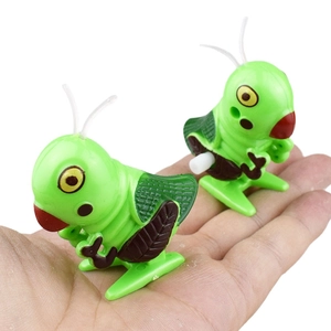 Close-up of green wind-up grasshopper toys held in hand showing compact size and details