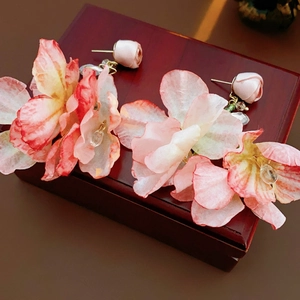 Detailaufnahme der rosa Netzblumenohrringe mit Kristallperlen auf einer Holzbox
