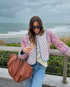 Outdoor shot of a pink floral quilted jacket paired with a brown leather tote bag