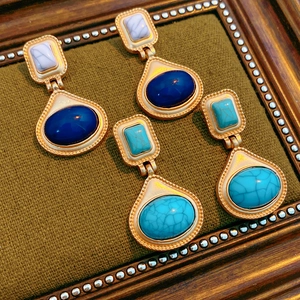 Detail view of vintage resin drop earrings with marble texture gems on textured fabric