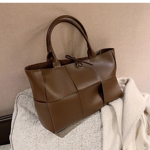 Detail of dark brown woven tote bag with drawstring closure on soft fabric