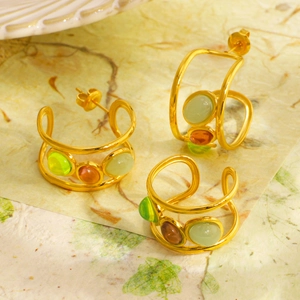 Three gold multi-layer hoop earrings with colorful natural stones on textured leaf paper