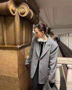 Detail of a dark grey oversized wool coat with peak lapel and 3D floral neck accessory