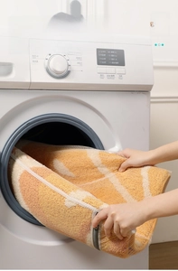Putting a large laundry mesh bag with a fruit pattern rug into a washing machine