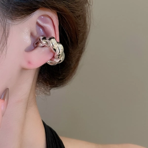 Gros plan d'un ear cuff torsadé argenté avec une texture métallique polie sur l'oreille