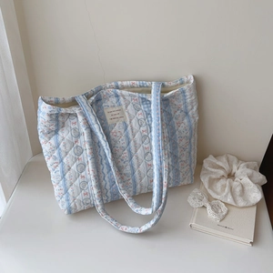 Detailed texture of blue and white quilted floral tote bag with cute rabbit patterns