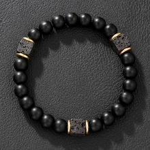 Dettaglio del bracciale di ematite nera con distanziatori dorati su pelle scura