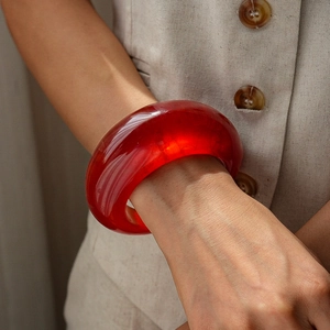 Close-up of translucent red resin wide bangle on model wrist with minimalist design