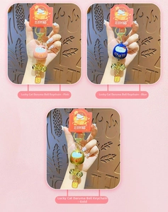 Detailed view of Maneki Neko Daruma charms in pink, blue, and gold with lucky bells