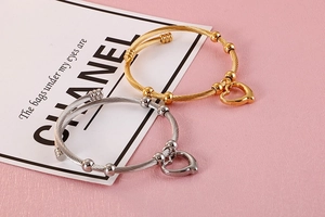Detail of cable texture bracelets in gold and silver with heart charms and sliding beads