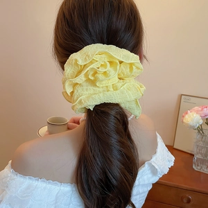 Detail of a large yellow textured fabric scrunchie on a woman ponytail in a soft room