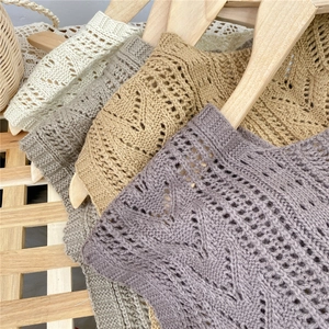 Hollow out knit shawls in beige, grey and purple draped on wooden hangers for spring