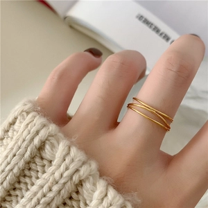 Detail of a minimalist triple-layered gold-plated ring worn over a beige knitted sweater