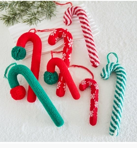 Detailed texture of knitted candy cane Christmas tree ornaments on white snowy background