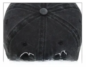 Close-up of the six-panel crown stitching and top button on a washed black denim baseball cap