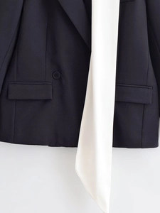 Detail of dark blue blazer featuring white contrast trim and hemline with button accents
