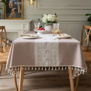 Brown jacquard tablecloth with reindeer patterns and fringe on a rectangular dining table