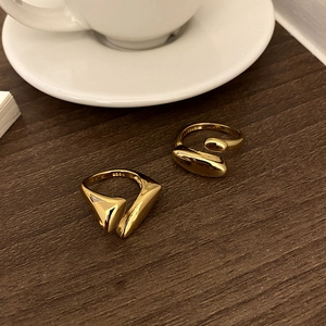 Macro shot of gold-plated irregular geometric rings and S925 engraving on wooden table