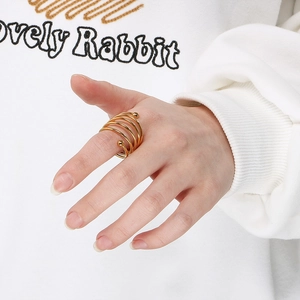 Detailed close-up of a golden spiral multi-layer ring with beads worn by a model