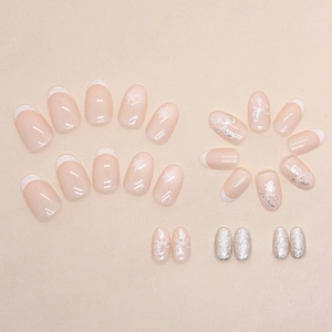 Oval French press-on nails featuring white snowflakes, bows and champagne glitter accents
