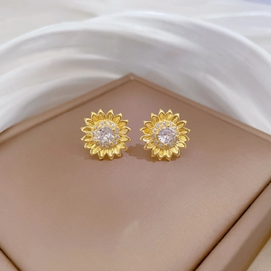 Macro shot of gold sunflower stud earrings with shimmering white cubic zirconia stones