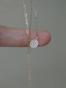 Macro shot of a tiny gold S925 sterling silver necklace with a micro-paved disk pendant