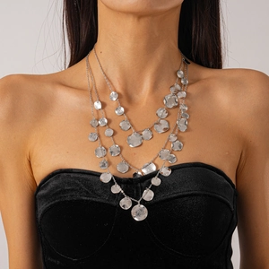 Close-up of three-layer silver necklace with hammered coin pendants on a black velvet top