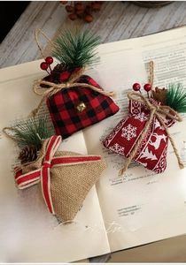 Three rustic Christmas burlap gift bags with pine cones and berries on vintage book pages