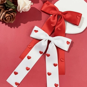Detail of red and white satin bow hair clips with heart patterns on a floral background