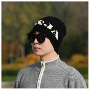 Close-up of black knitted beanie with white letter embroidery for outdoor winter wear