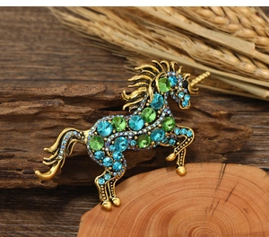 Detailed vintage unicorn brooch with vibrant blue and green rhinestones on rustic wood