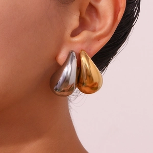 Close-up of gold and silver large teardrop earrings with a glossy mirror finish