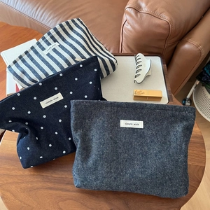 Three canvas cosmetic bags with stripes and dots on a wooden table for daily storage