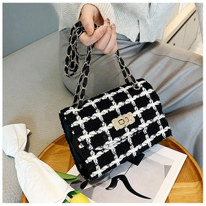 Close-up of black and white tweed crossbody bag with woven chain strap and metal lock