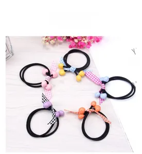 Five-pack set of colorful beaded bow hair ties in various macaron colors on wood base