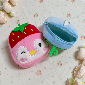 Plush penguin coin purse with strawberry hat and blue fruit bag on floral background