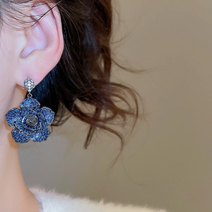 Close-up of blue floral drop earring with sparkling crystals on female model