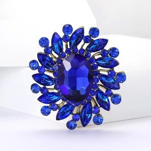Detailed macro view of vintage sunburst brooch featuring blue crystals and gold-tone metal base
