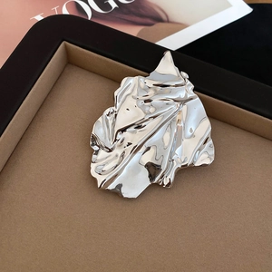 Macro view of silver pleated leaf brooch with mirrored texture and abstract metal folds
