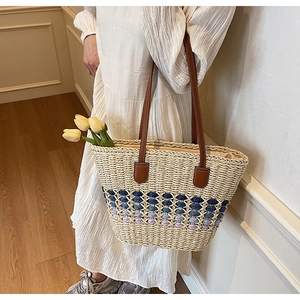 Detail of straw tote bag with blue gradient weave and brown leather handles