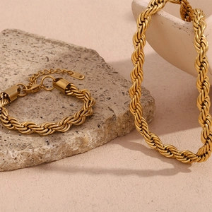 Detail of 18K gold plated rope chain necklace and bracelet set on a natural stone base