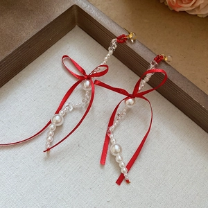 Detail of elegant long tassel earrings with red silk ribbon bows and pearl bead strands