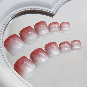Sparkly red and white ombre cat-eye press-on toenails on a pearl mirror display