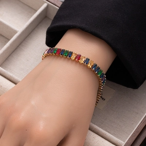 Detail of colorful rectangular zircon tennis bracelet with gold finish on wrist