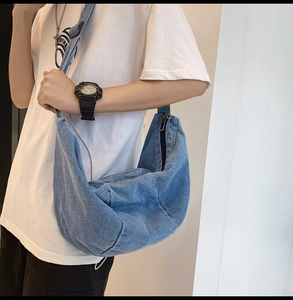 Detailed view of a vintage blue washed denim crescent bag with a silver side zipper